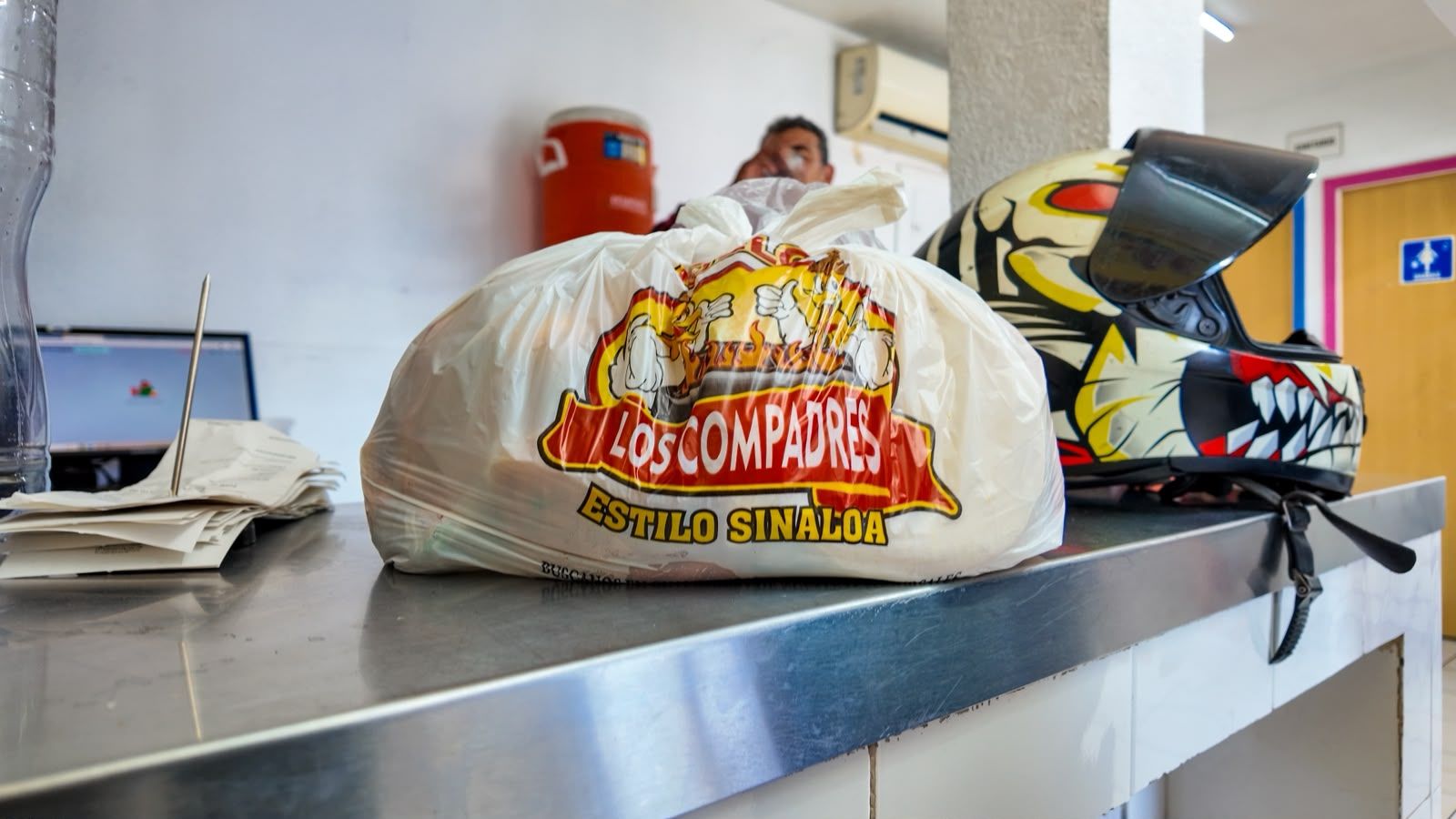 Bolsa de Los Compadres sobre la barra de la sucursal Vicente Guerrero, junto a un casco de repartidor