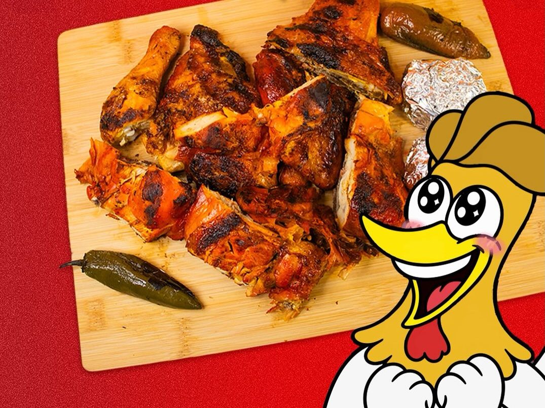 Pollo entero asado en piezas sobre una tabla de madera, con chiles toreados, y el gallo de la marca asomado